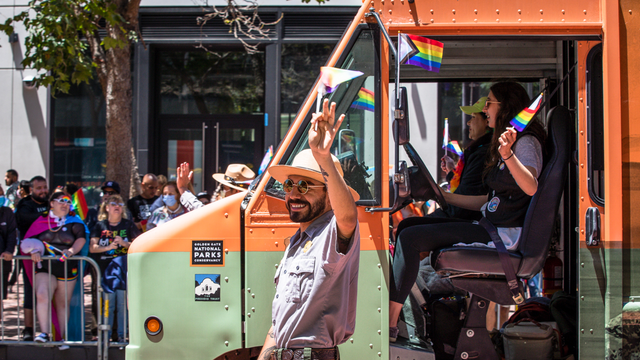 NPS park ranger marches alongside the Roving Ranger mobile trailhead at the 2022 SF Pride parade.