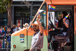 NPS park ranger marches alongside the Roving Ranger mobile trailhead at the 2022 SF Pride parade.