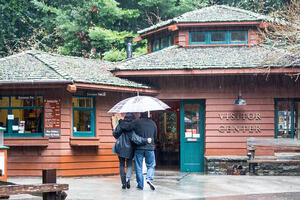 People head toward the Visitor Center under an umbrella on a rainy day