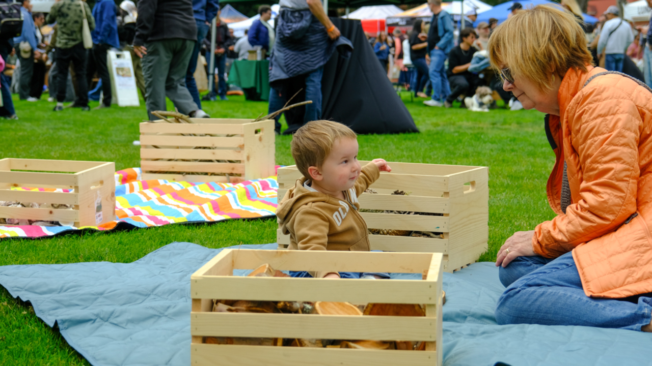 A parent or guardian watching a child play on the Presidio lawn in san francisco during the Parks4All: Brewfest