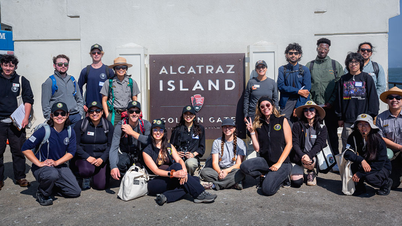 2024 Academic Interns and Conservancy Fellows pose in front of the Alcatraz Island sign after touring the island and stewarding the Alcatraz Garden.