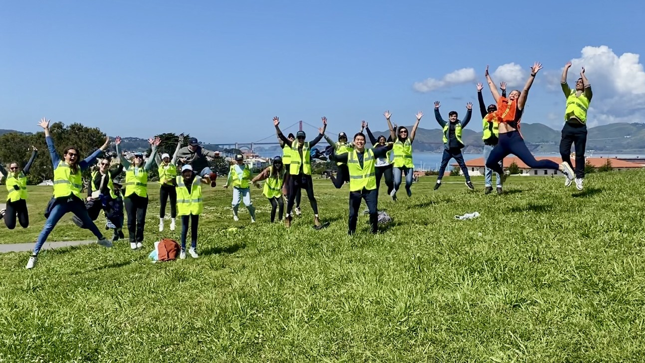 A group of volunteers jump for a photo in front of the Golden Gate Bridge