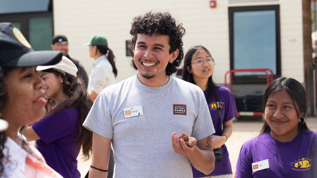 Parks Conservancy staff smiles while interacting with others at Crissy Field Center.