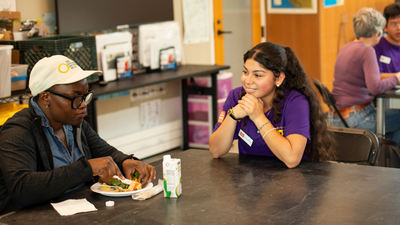 Youth program participant sits with a woman eating food at the Crissy Field Center in the Presidio during the Goldman Prize Awards Youth Reception.