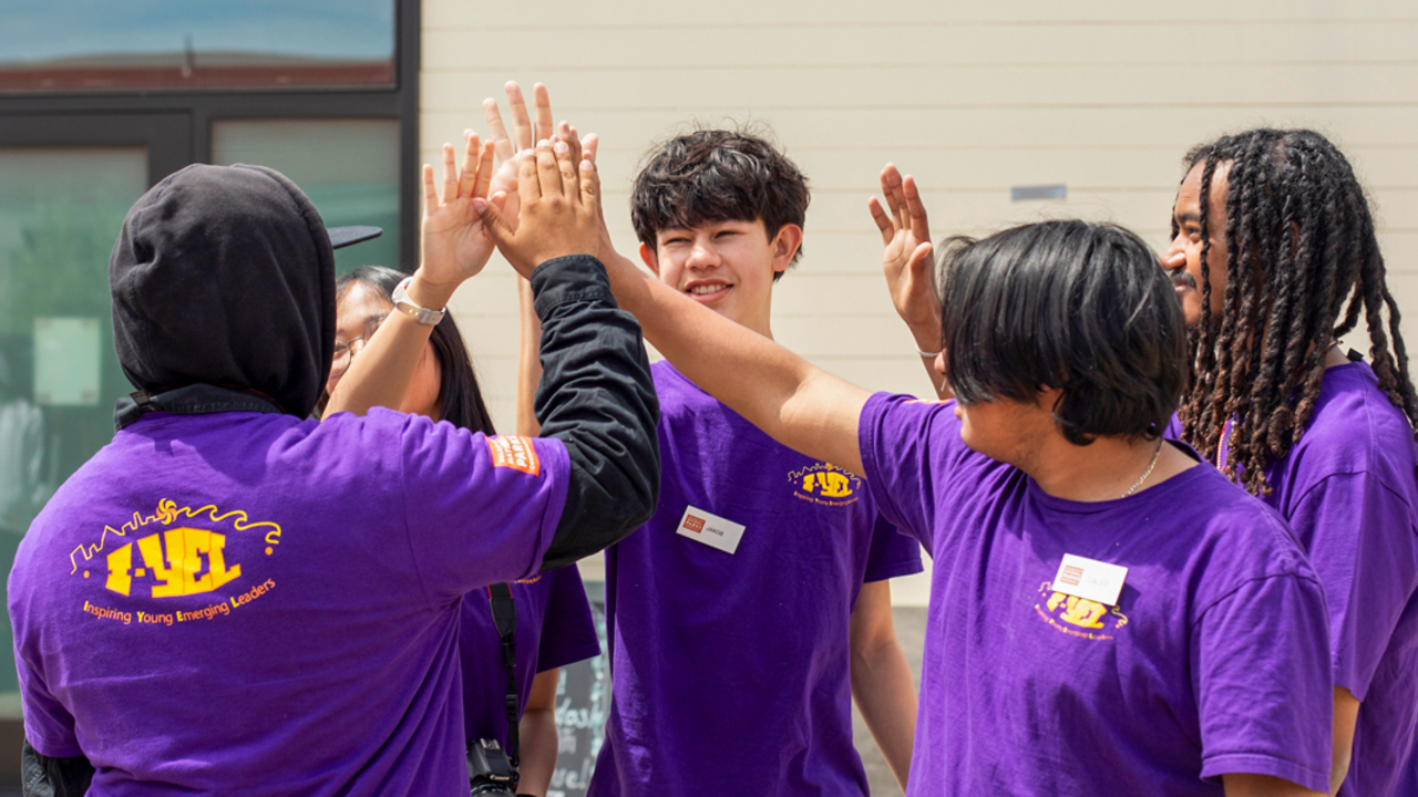 A group of Crissy Field Center youth participants giving high fives at the Presidio.