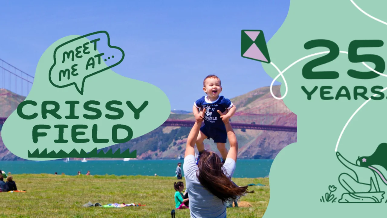 a parent holds their smiling child in the sky at Crissy Field with the Golden Gate Bridge in view.
