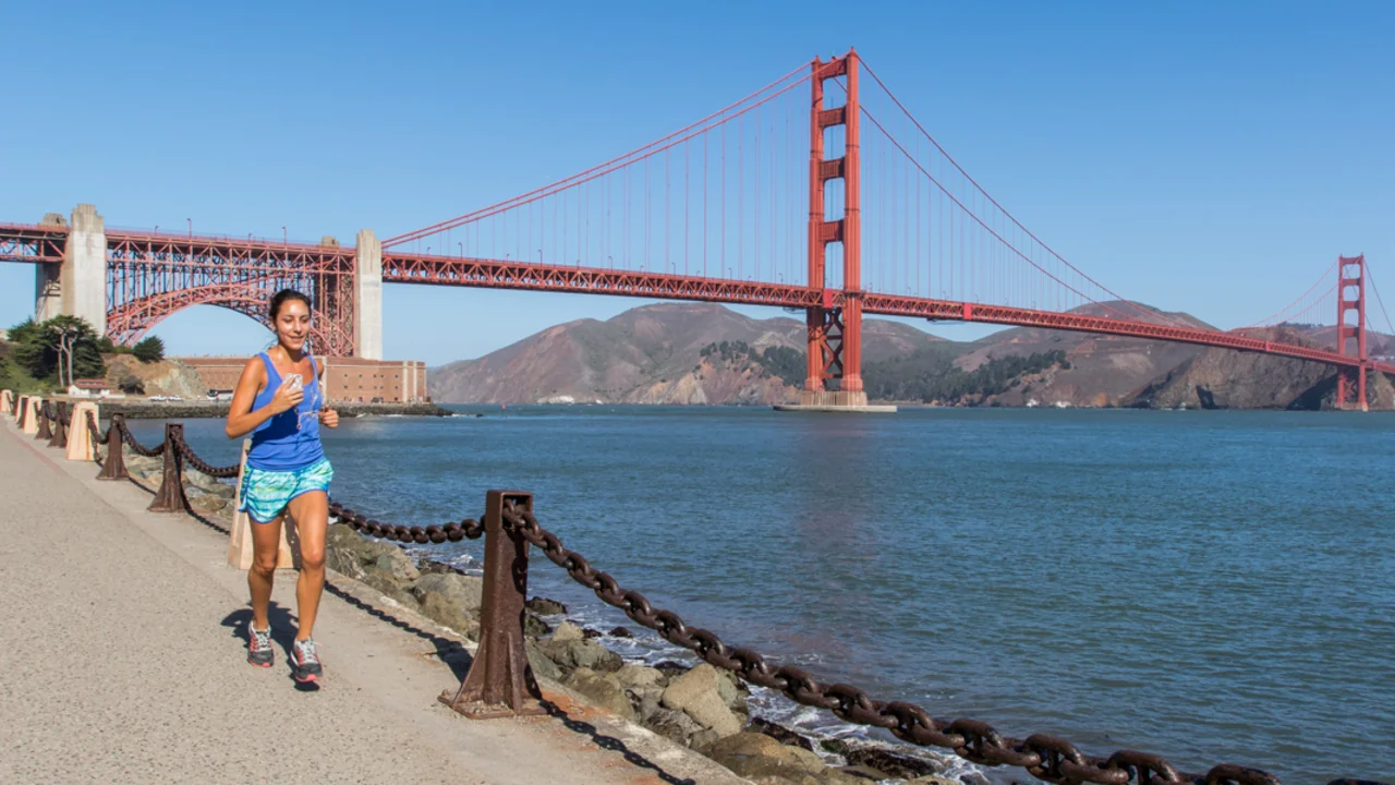 A jogger on the waterfront path from Fort Point in San Francisco. The Golden Gate Bridge and SF bay in the background.
