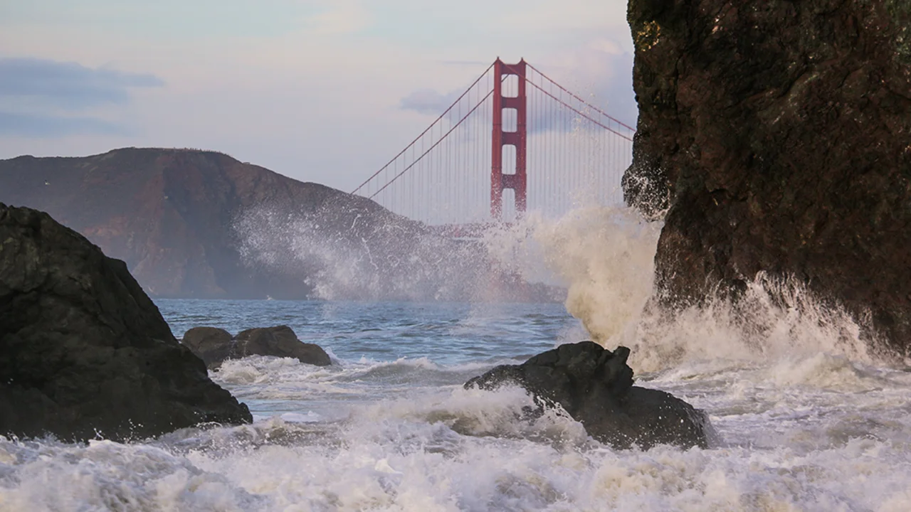 Waves crash before the Golden Gate Bridge