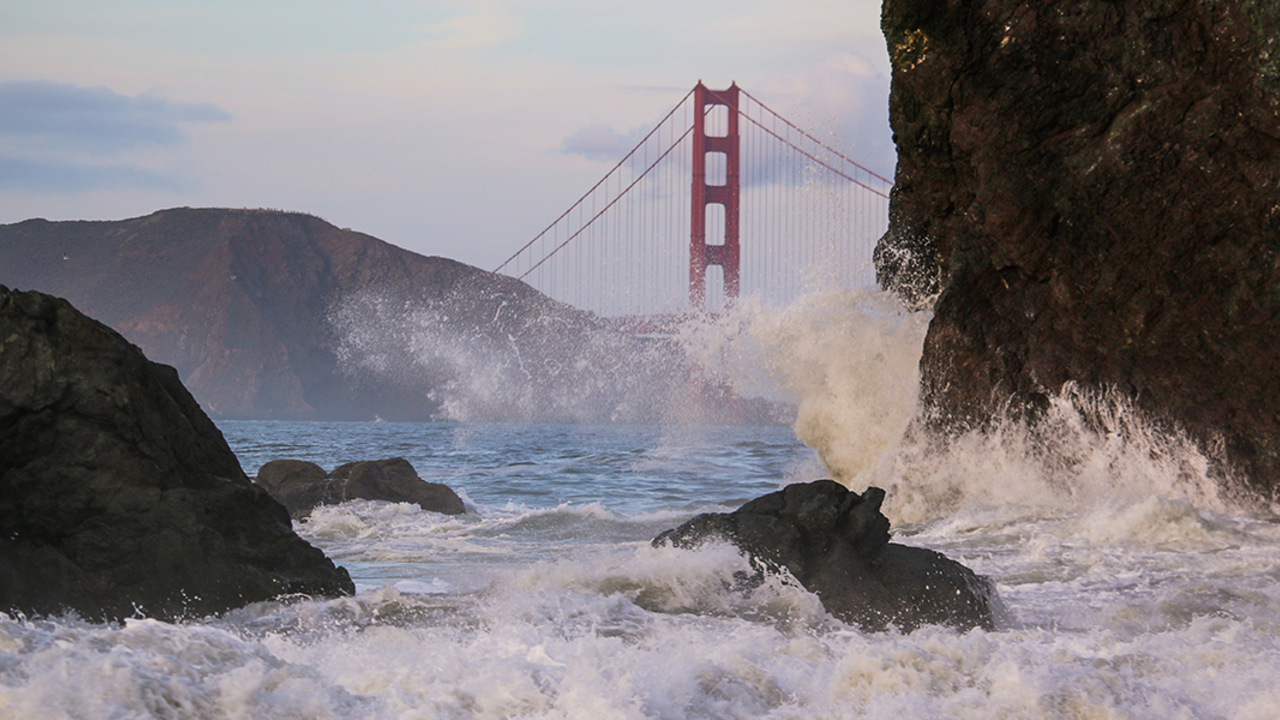 Waves crash before the Golden Gate Bridge