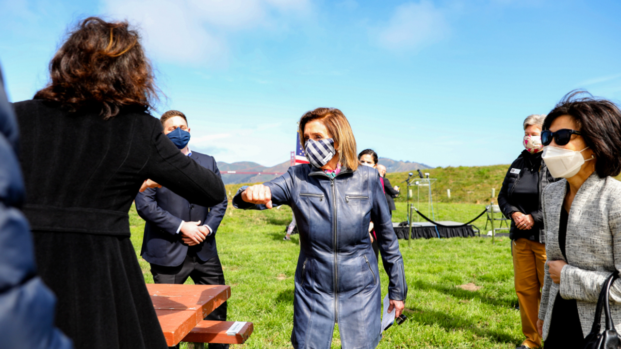 Speaker Nancy Pelosi elbow bumps to greet attendees at Crissy Field's 20th anniversary address