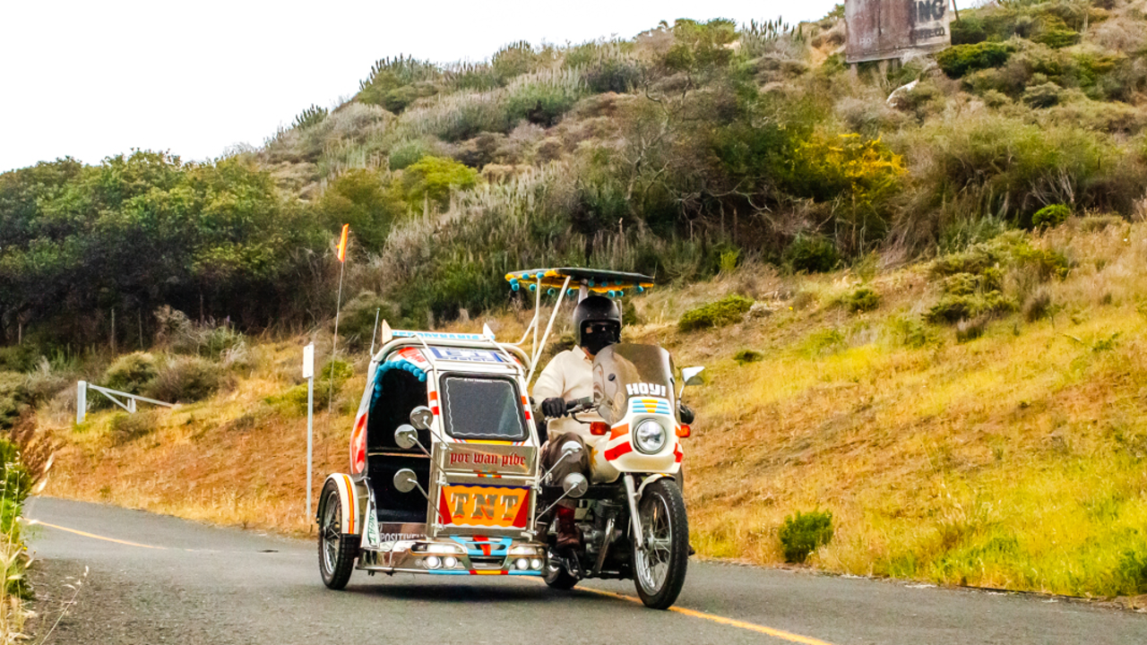 A motorcycle with a sidecar drives down a two-lane road.