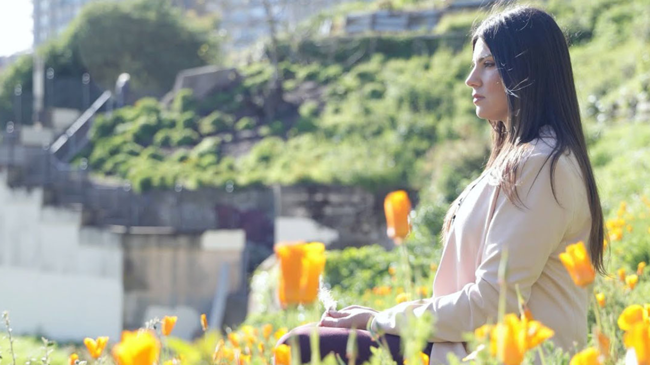 Sharaya Souza sits surrounded by orange poppies.