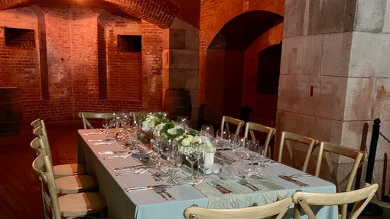 A fancy dining table is set in the brick hall of Fort Point.