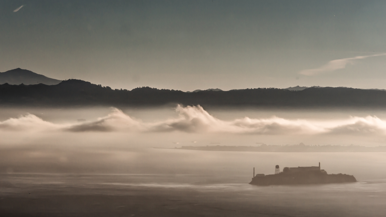 HAHI_20211111_ATB_61_2x1.jpg Alcatraz Island is pictured in the distance with dramatic gray clouds overhead.