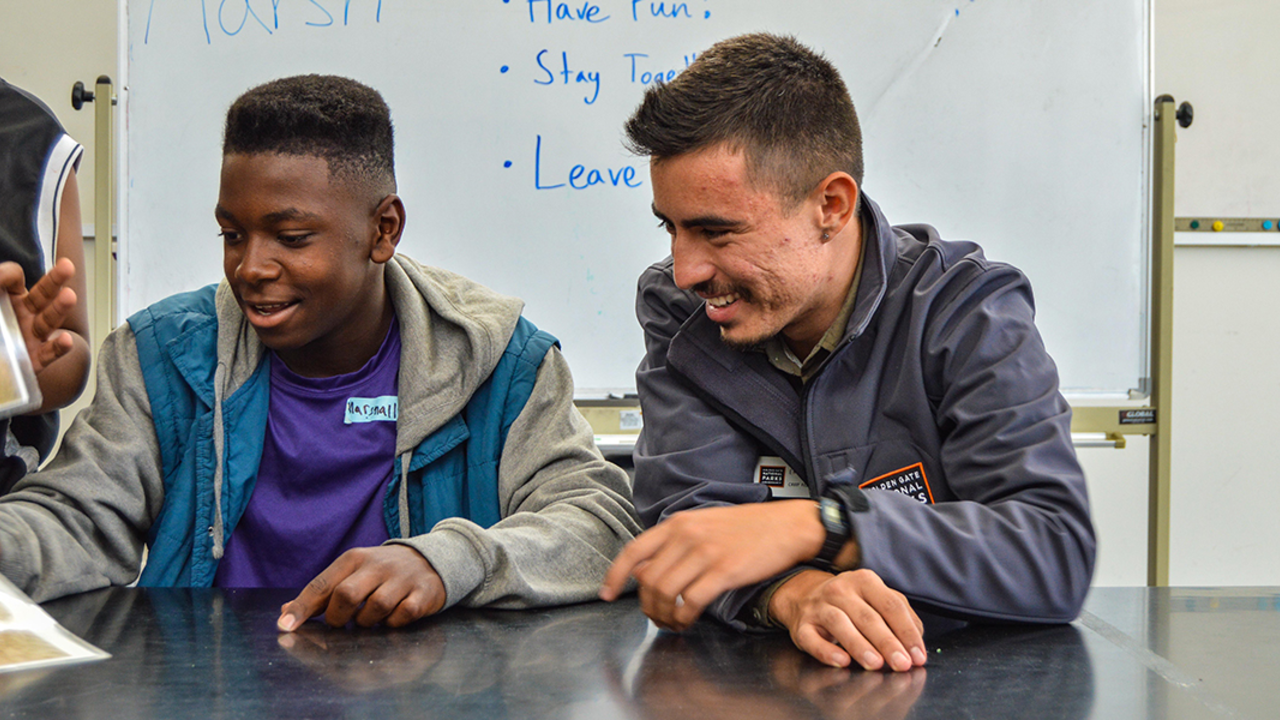 A Crissy Field Center educator a teenage youth look over images inside the Crissy Field Center facility