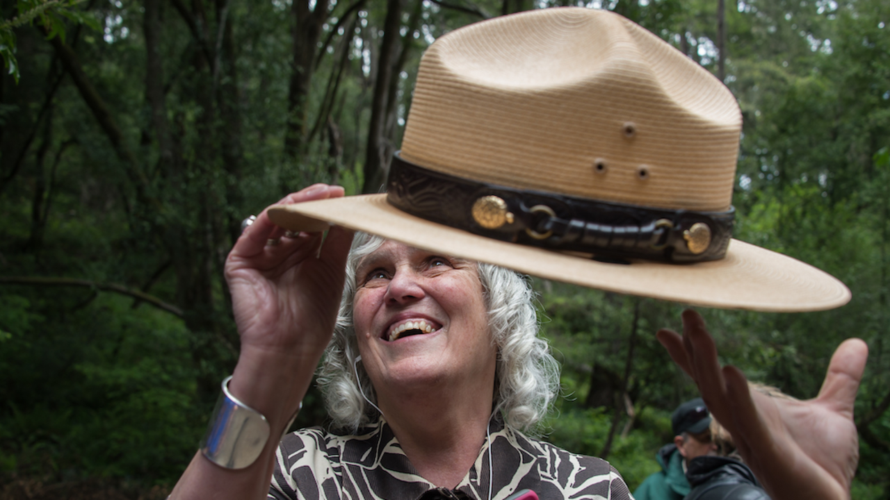 A blind woman feels the NPS ranger hat with her hands. 