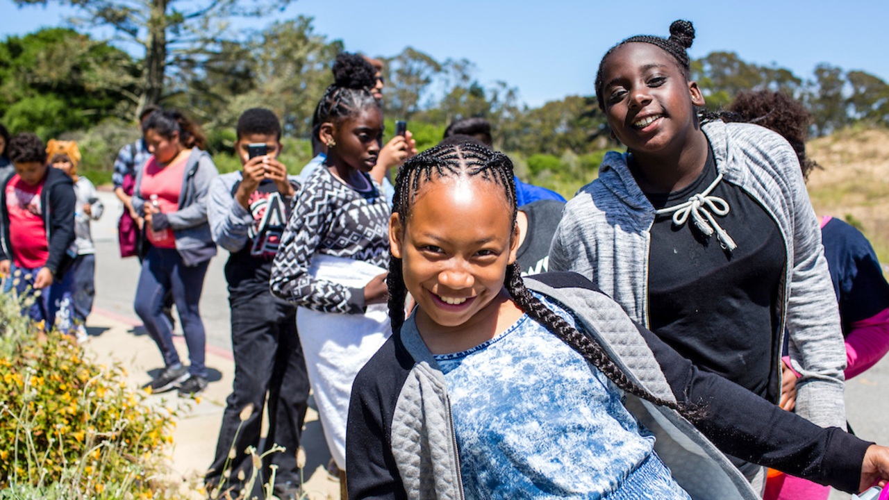 A youth group smiling as they hike through Presidio trails in San Francisco