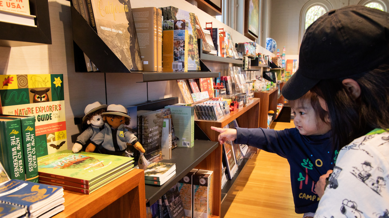 Kid pointing towards national park-themed merchandise at the Presidio Visitor Center in the San Francisco Bay Area.
