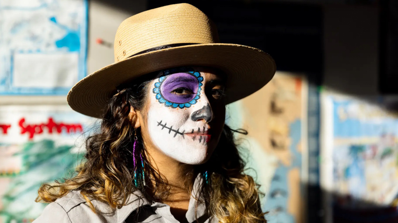 A portrait of an  NPS ranger with candy skull face paint on for Dia de los Muertos.