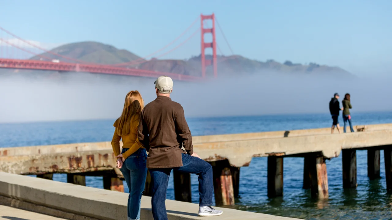 A couple stops to take in a Golden Gate Bridge view at Crissy Field East Beach