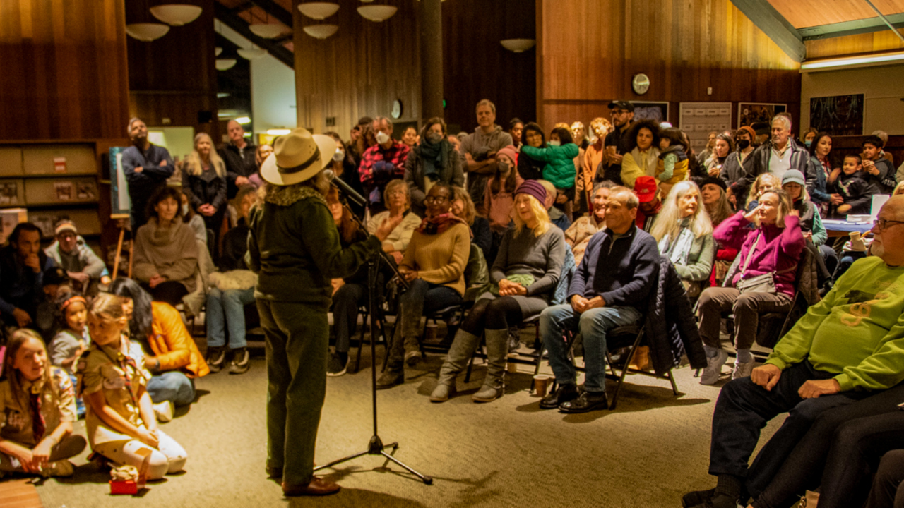 A National Park Service ranger speaks to a seated crowd in the Mill Valley Public Library during the Winter Solstice Celebration