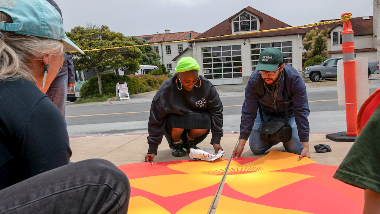 Artist and workers install adhesive artwork onto the sidewalks at Presidio Tunnel Tops