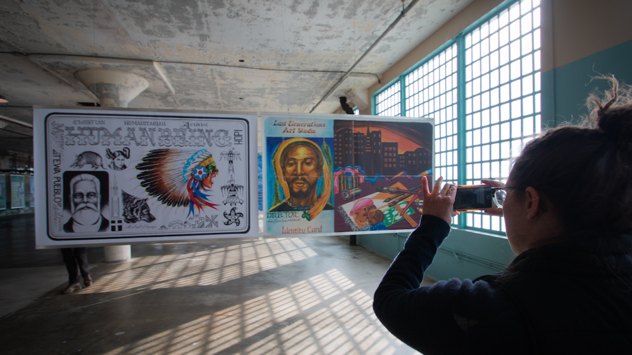 Woman takes photo of Future IDs display in the New Industries Building on Alcatraz.