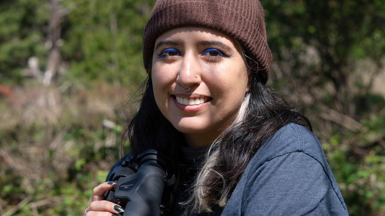 Portrait of birder Daniela Sánchez with binoculars on a birding trip. Portrait of birder Daniela Sánchez with binoculars on a birding trip.