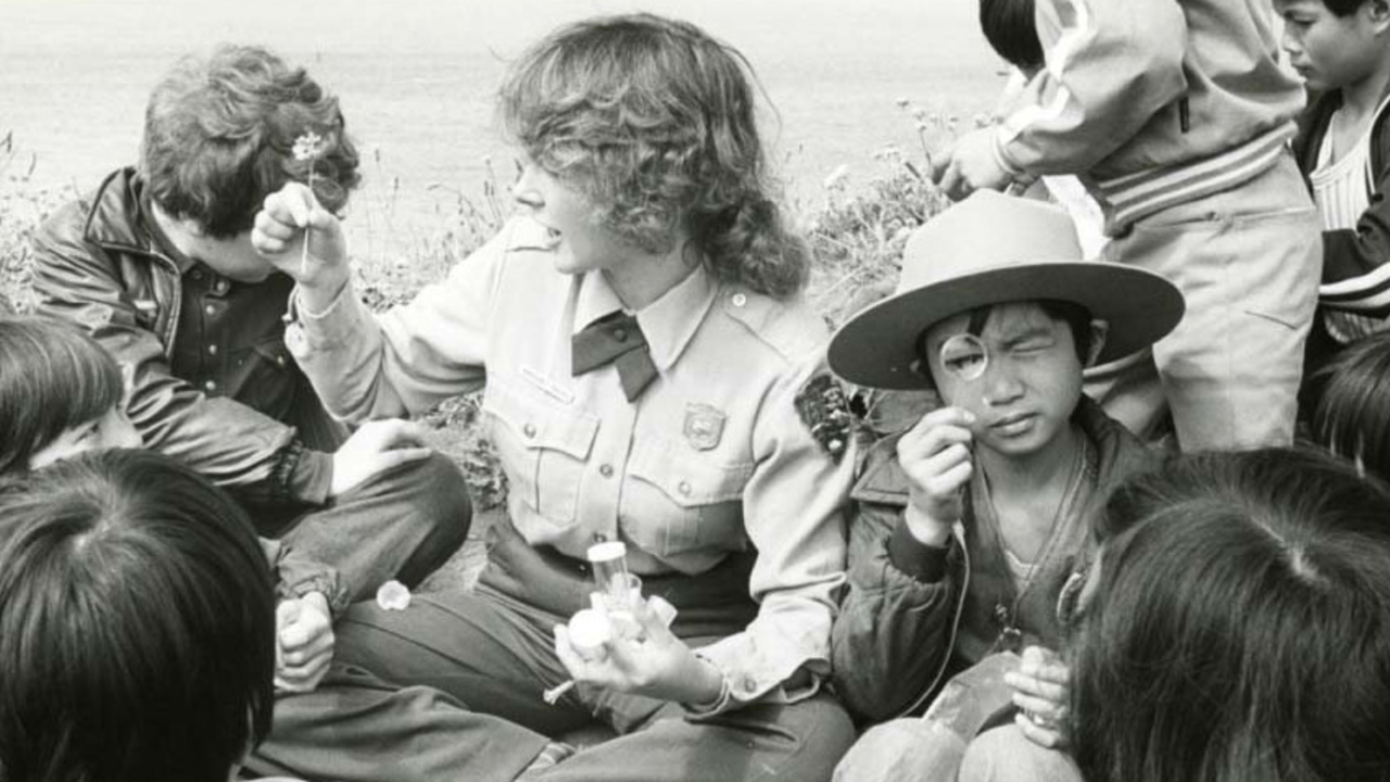 NPS park ranger, children gather and examine flowers in black and white historic photo from 1978. NPS park ranger, children gather and examine flowers in black and white historic photo from 1978.