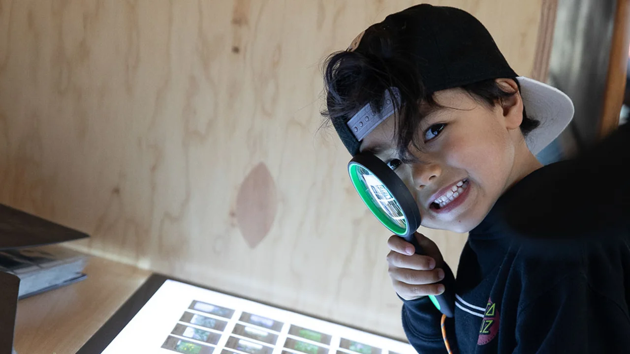 Youth with magnifying glass looking at slides at Presidio Tunnel Tops.