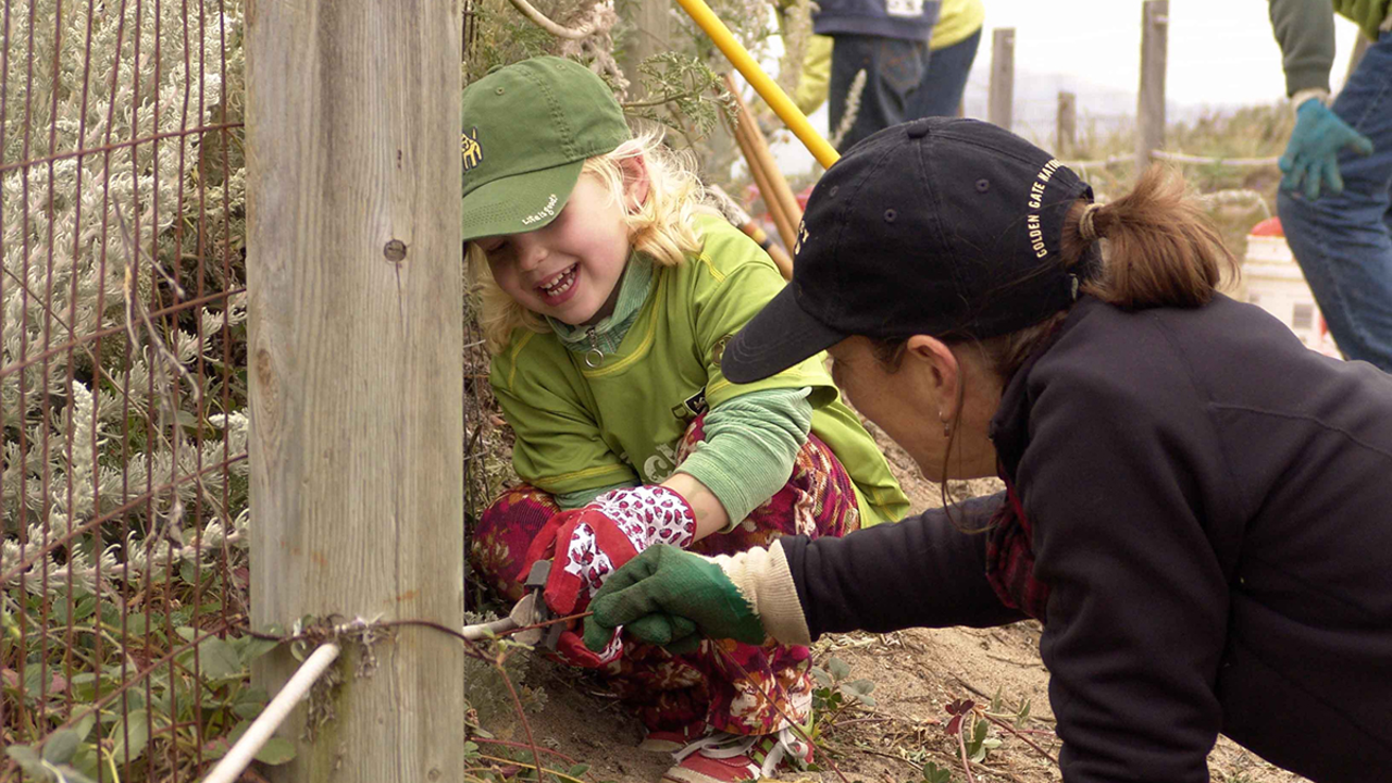 A child and her mother help plant native vegetation at Crissy Field