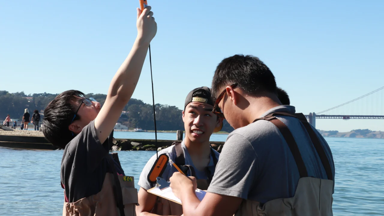 A small group of teenagers uses monitoring tools in the waters off of Crissy Beach