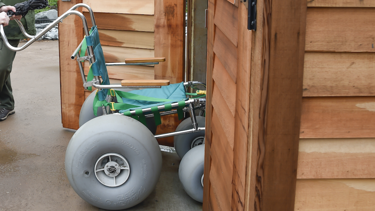 NPS Ranger pushes beach wheelchair into storage