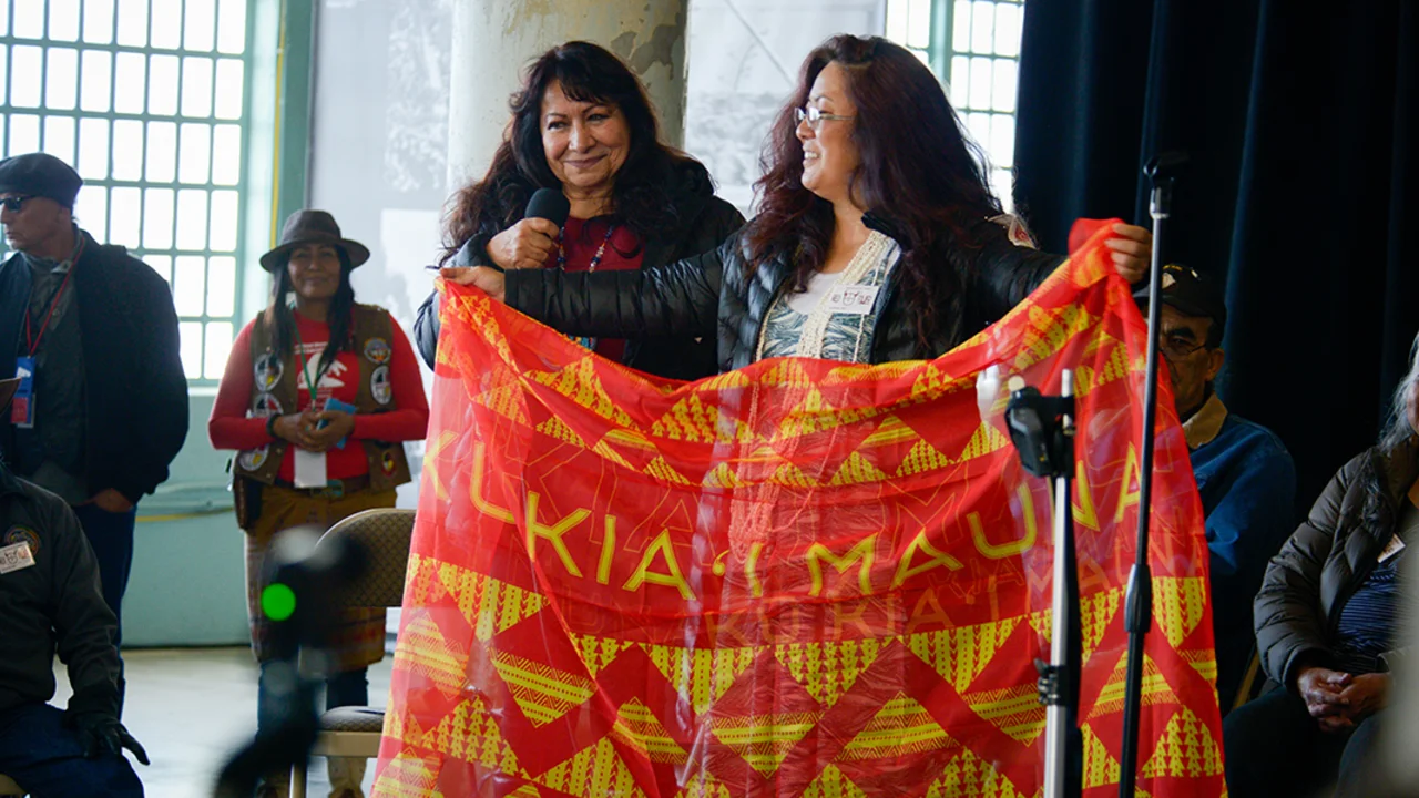 two woman on stage with banner