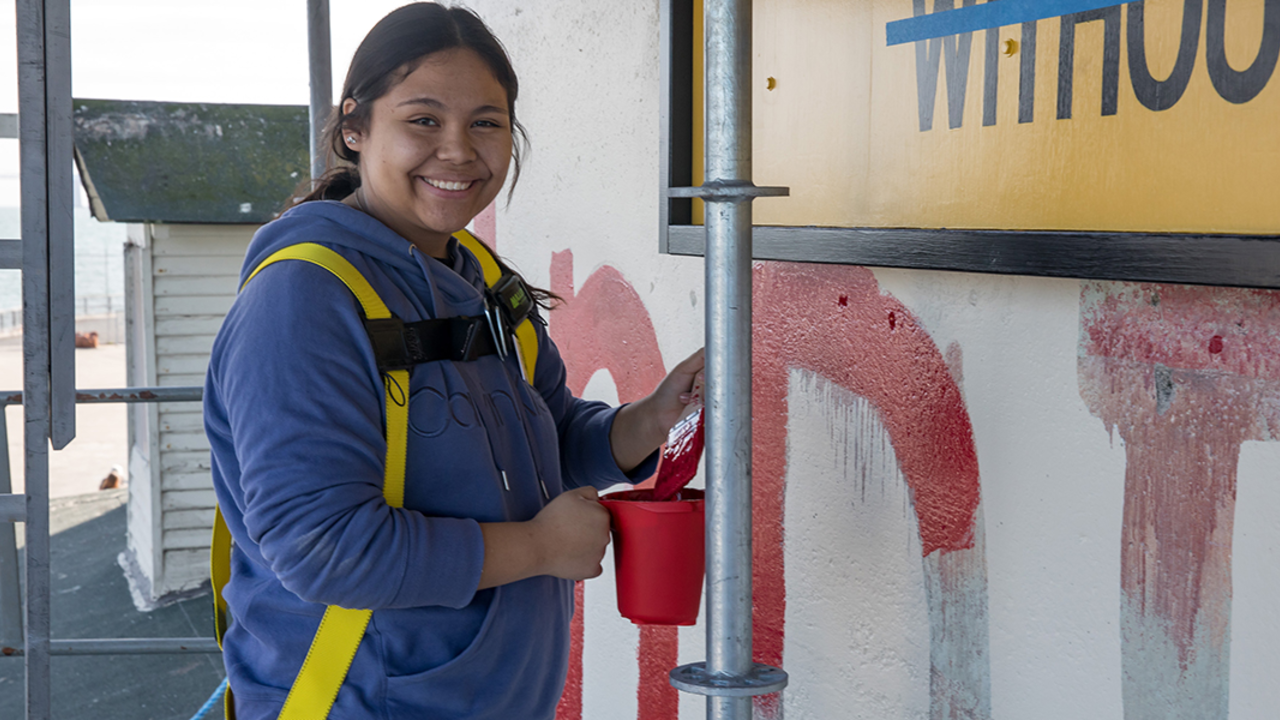 girl posing for picture with paintbrush