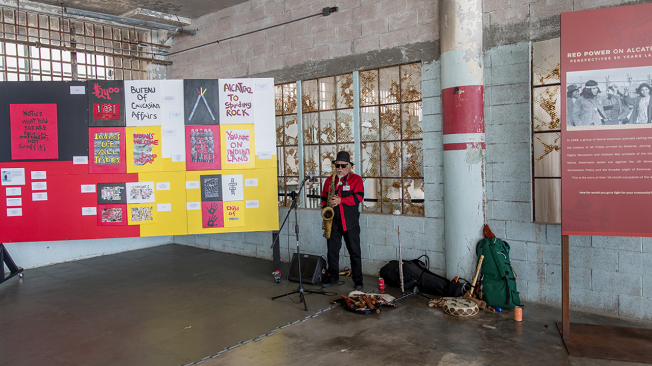 Man playing saxophone surrounded by slogans about Red Power on Alcatraz