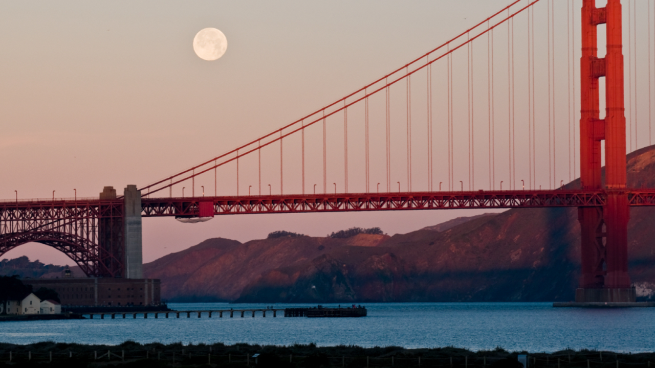 The moon rises above the bridge