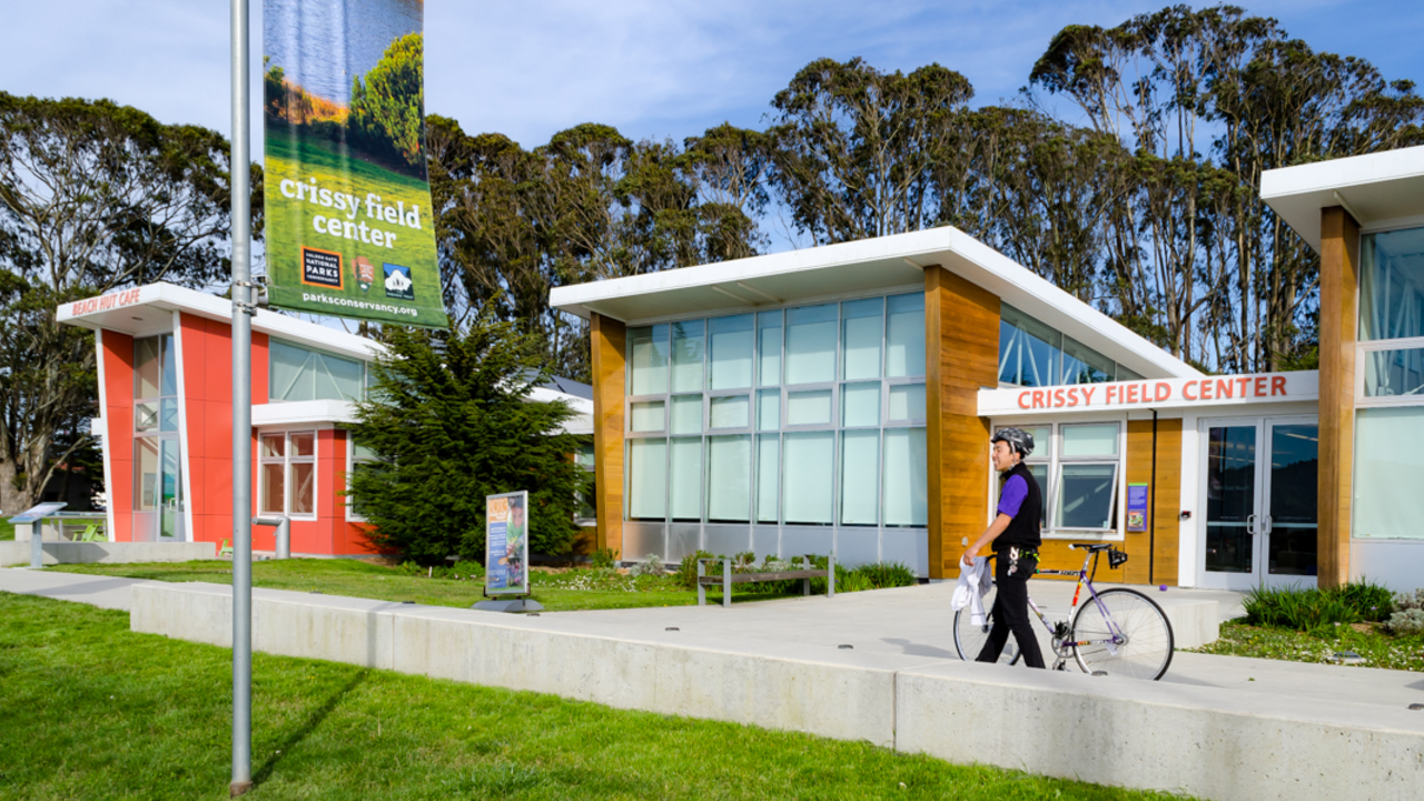Crissy Field Center at Crissy Field. A park visitor at Crissy Field walks his bike by Crissy Field Center.