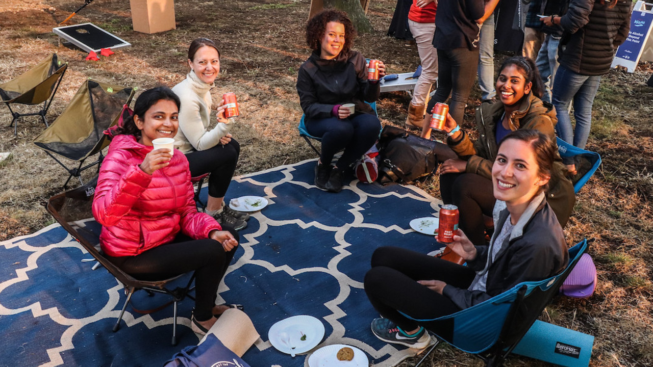Five friends sitting outside at Sutro Heights Park holding up Fort Point Beer cans.