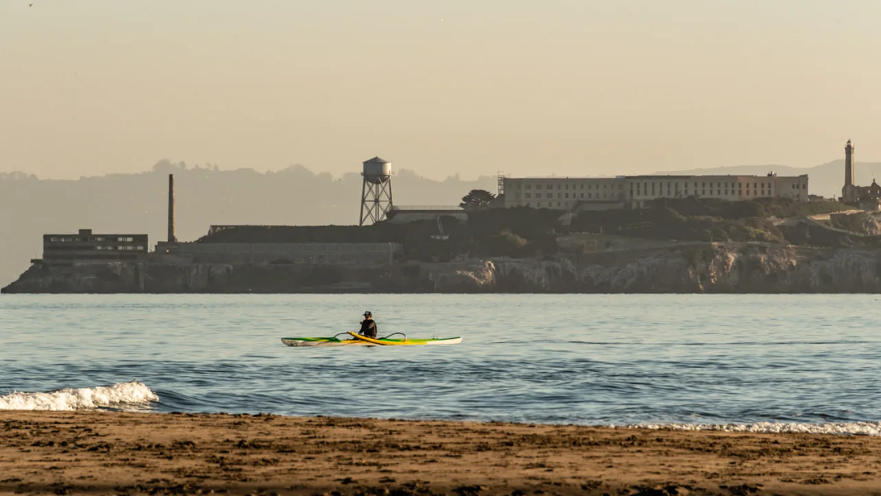 A Kayak paddles over the Golden Gate waters, viewed before Alcatraz Island from Crissy Field East Beach.
