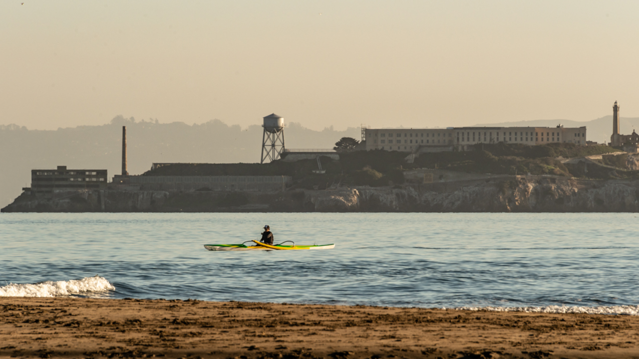 A Kayak paddles over the Golden Gate waters, viewed before Alcatraz Island from Crissy Field East Beach.