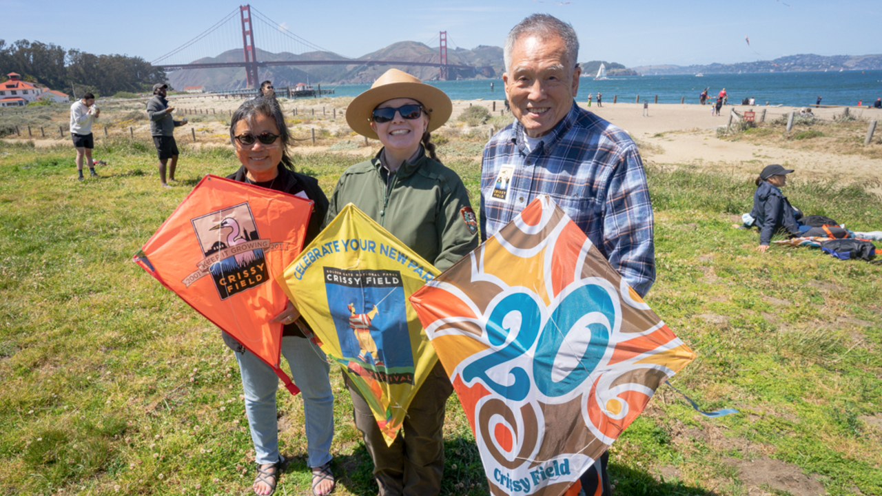 Conservancy, NPS, and the owner of Chinatown Kite Shop pose with Crissy Field commemorative kites. Conservancy, NPS, and community representatives pose with commemorative kites at Crissy Field Kite Day
