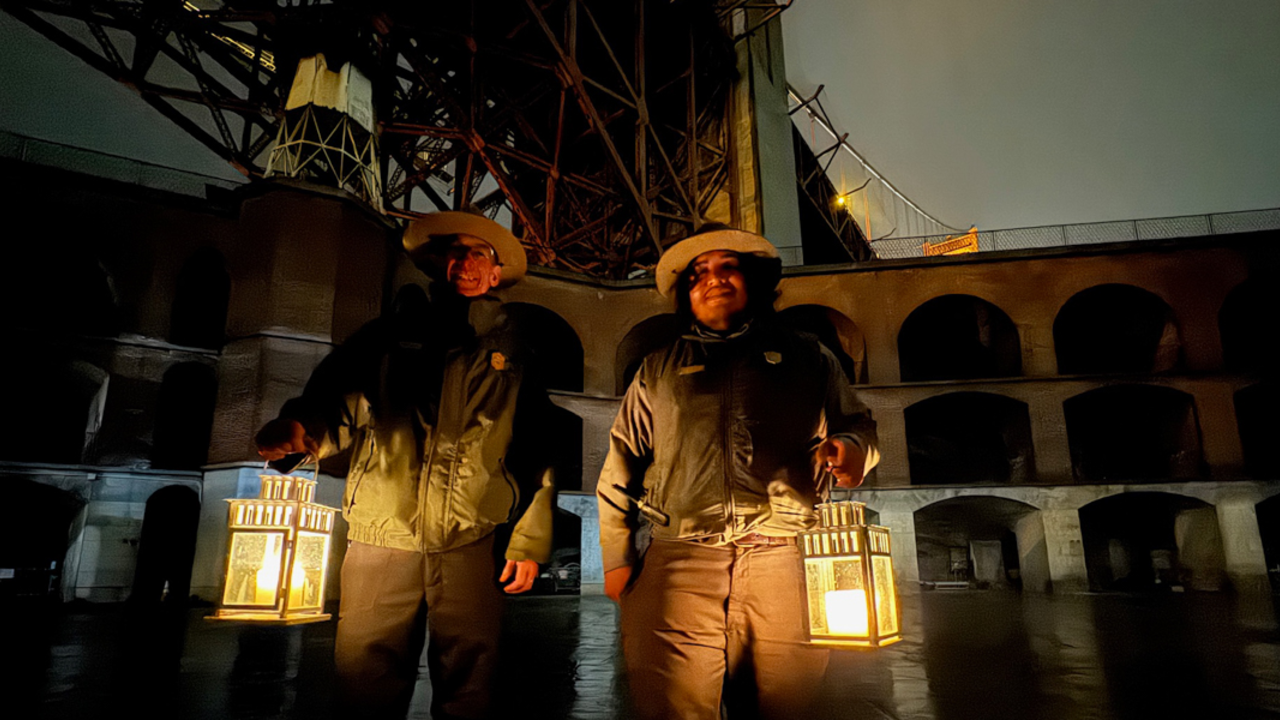 NPS Rangers lead the candlelight tour at Fort Point Two NPS National Parks Service rangers holding lanterns at Fort Point for a candlelight tour