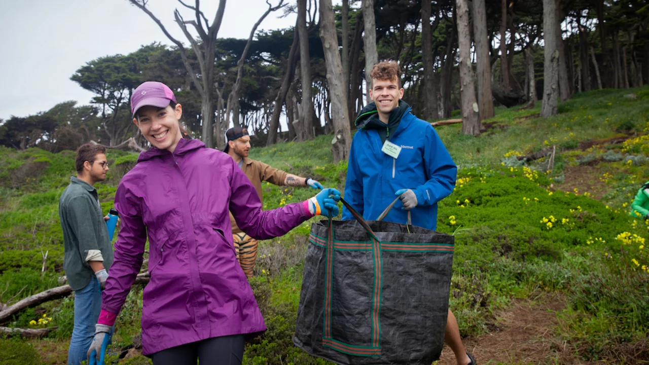 Two volunteers hold up bag full of weeds at Lands End in San Francisco