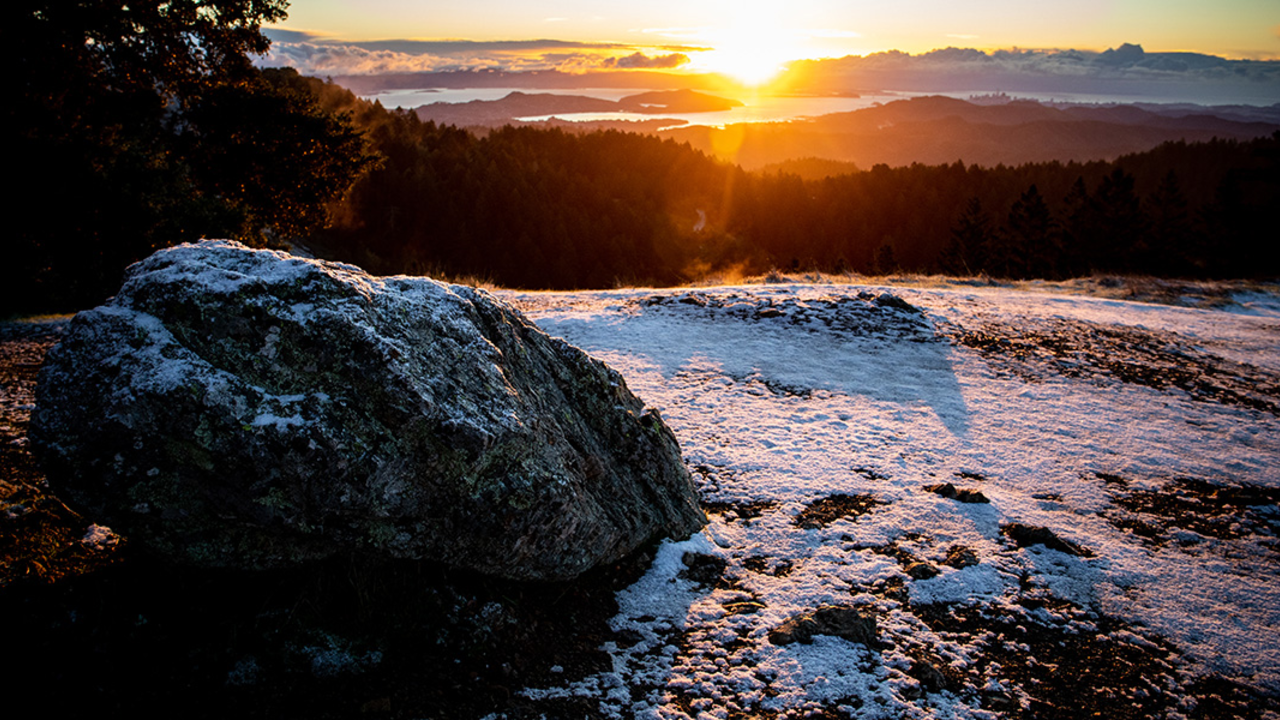 Snow on a boulder on mount tam at sunrise.
