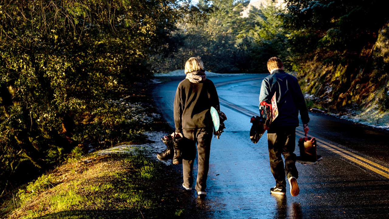 Hoping for the best Teens with snowboards walk towards snow.