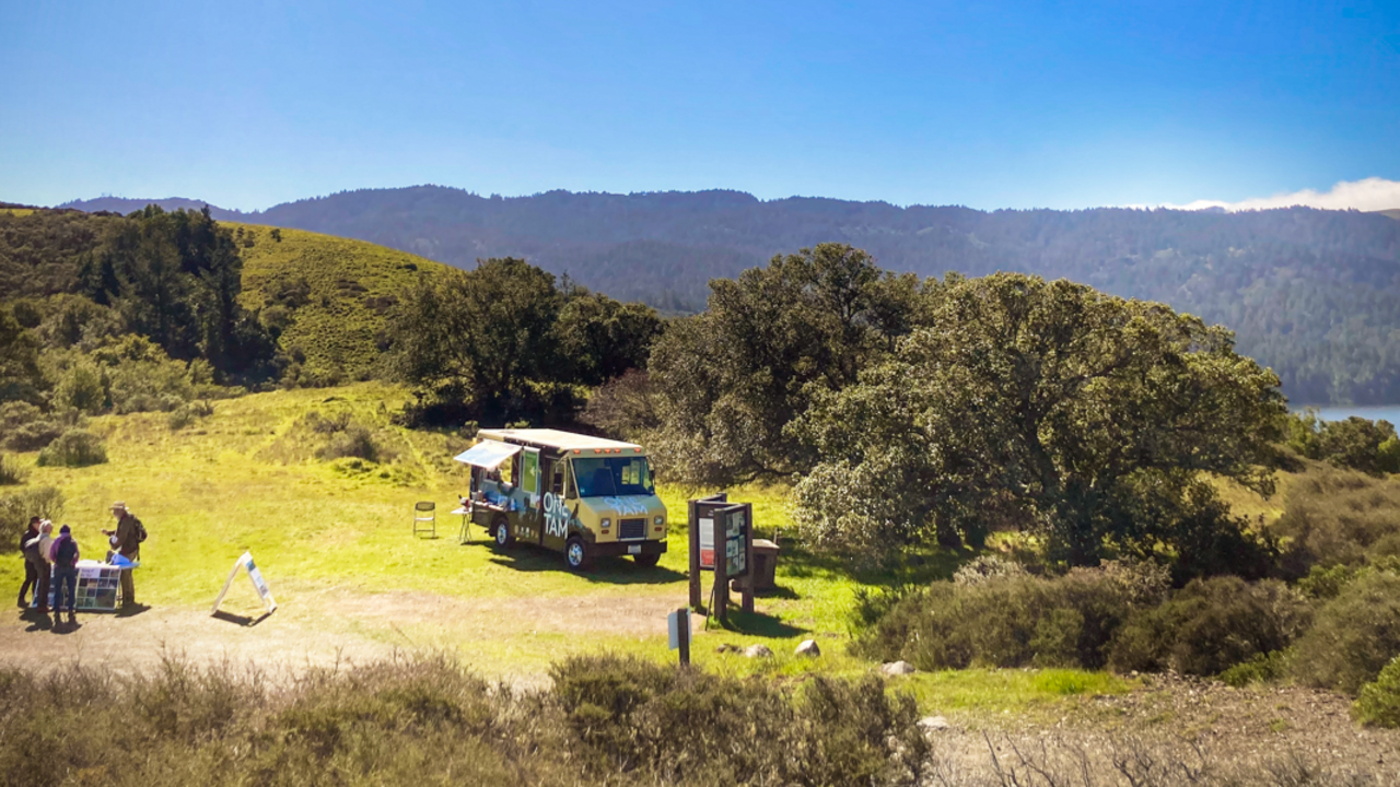 The One Tam Van at Mount Tamalpais A scenic landscape from Mount Tamalpais. The One Tam Tam Van is parked in the grass with visitors about.