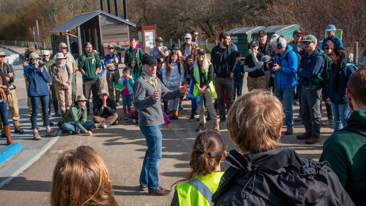 U.S. Fish and Wildlife Service representative gives speech to a encircled crowd at Muir Beach before releasing coho salmon into Redwood Creek. 