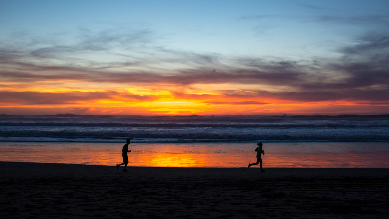 Evening Exercise at Ocean Beach. Park visitors are going for a jog along the gorgeous red sunset and lapping waves at Ocean Beach.