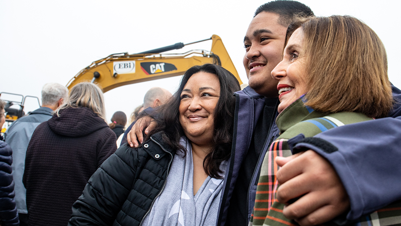 PRSF_20191107_PMM_0894.jpg Three people embrace in front of excavator.